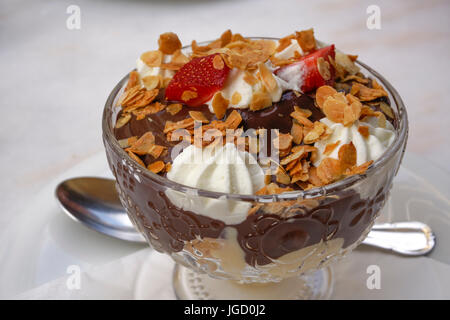 Blätterteig mit dunkler Schokolade Choux bedeckt mit Sahne, garniert mit Mandeln und Erdbeeren. Stockfoto