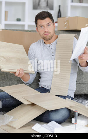 frustriert Mann Anleitung lesen und Zusammenstellung Selbstmontage Möbel Stockfoto