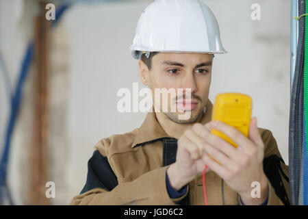 Baumeister, die Kalibrierung eines Geräts auf einer Baustelle Stockfoto