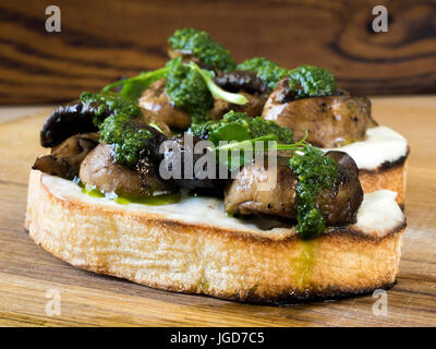 Bruschetta mit gebackenen Champignons, Frischkäse und Spinatsauce Stockfoto