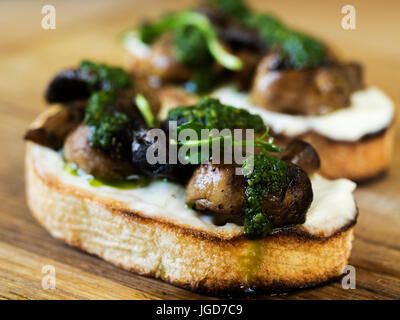 Bruschetta mit gebackenen Champignons, Frischkäse und Spinatsauce Stockfoto