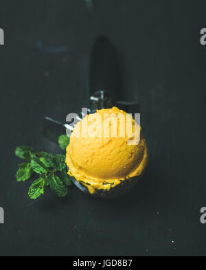 Mango-Sorbet Eisportionierer Scooper auf schwarzem Hintergrund Stockfoto