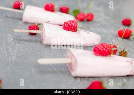 Himbeer Eis auf grauem Hintergrund. Drei hausgemachtes Eis am Stiel. Stockfoto