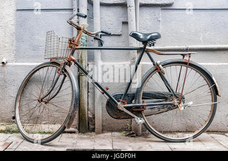 Alte und rostige Fahrrad Parken gegen eine graue Stadtmauer Stockfoto