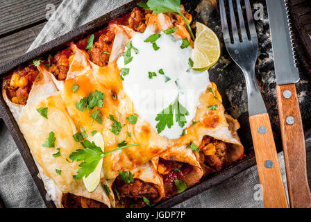 Mexikanisches Essen. Küche von Südamerika. Traditionelles Gericht der würzige Rindfleisch Enchiladas mit Mais, Bohnen, Tomaten. Auf ein Backblech, auf alten rustikalen hölzernen bac Stockfoto