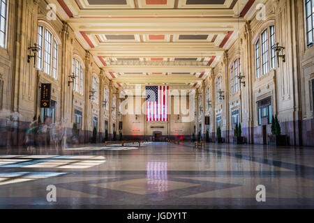 Horizontale Foto des Innenraums von der Union Station in Kansas City, MO mit einer großen amerikanischen Flagge auf die Rückwand und die Menschen verwischt Stockfoto