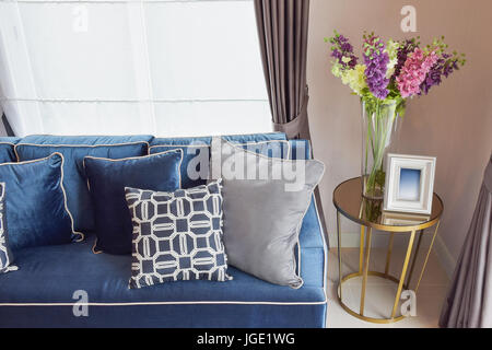 Marineblaue klassisches Sofa und Retro-Kissen mit einer schönen Orchideen Vase auf Beistelltisch im Wohnbereich Stockfoto