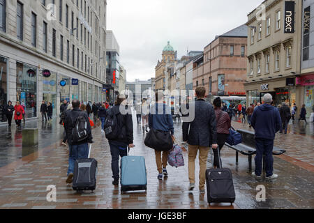 Glasgow Straße Touristen mit Gepäckwagen Argyle Street Glasgow Schottland nassen verregneten Oberfläche entlang Stockfoto