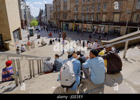 Touristen und Einheimische genießen das sonnige Wetter auf den Stufen der Sauchiehall Street in der Nähe von Donald Dewar-statue Stockfoto