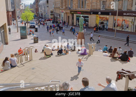 Touristen und Einheimische genießen das sonnige Wetter auf den Stufen der Sauchiehall Street in der Nähe von Donald Dewar-statue Stockfoto
