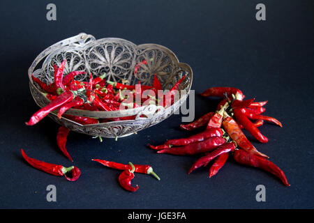 Rote Chilischote in eine silberne Vase auf einem schwarzen Hintergrund. Stockfoto