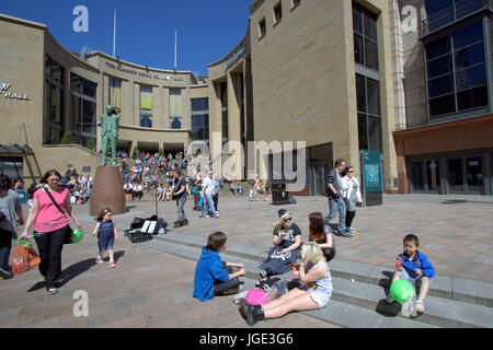 Touristen und Einheimische genießen das sonnige Wetter auf den Stufen der Sauchiehall Street in der Nähe von Donald Dewar-statue Stockfoto