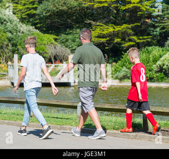 Vater und Söhne zusammen spazieren durch einen Park an einem warmen Tag im Sommer. Stockfoto