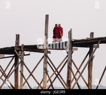 Mönche gehen auf die Ubein Brücke in Mandalay, Myanmar. Ubein wurde um 1850 erbaut und ist vermutlich die älteste und längste Teakholz Brücke in th Stockfoto