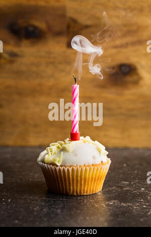 Cupcake mit einer Kerze am Tisch geblasen. Stockfoto