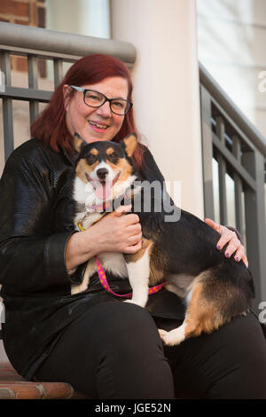 Porträt des kaukasischen Frau sitzt am Treppenabsatz mit Hund Stockfoto