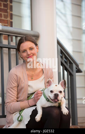 Porträt des kaukasischen Frau sitzt am Treppenabsatz mit Hund Stockfoto