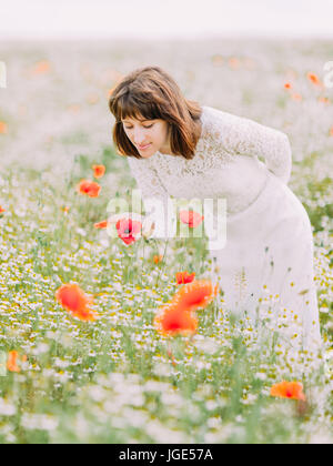 Die vertikale Ansicht der Braut berühren und riechen Mohn im Feld. Stockfoto