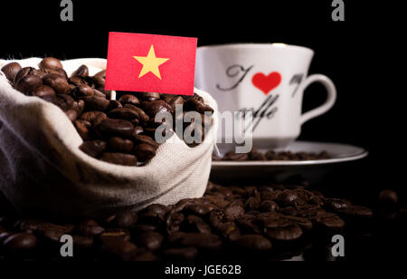 Vietnamesische Flagge in einer Tasche mit Kaffeebohnen auf schwarzem Hintergrund isoliert Stockfoto