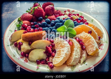 Eine Nahaufnahme von einer Platte mit gemischten Früchten wie Erdbeeren, Orangen, Blaubeeren, Äpfel und Bananen Stockfoto