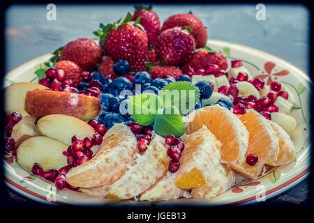 Eine Nahaufnahme von einer Platte mit gemischten Früchten wie Erdbeeren, Orangen, Blaubeeren, Äpfel und Bananen Stockfoto