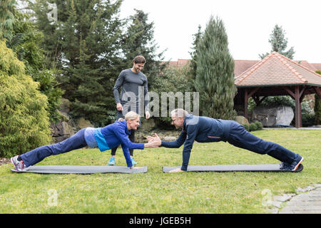 Paar übt mit einem personal Trainer im Garten Stockfoto