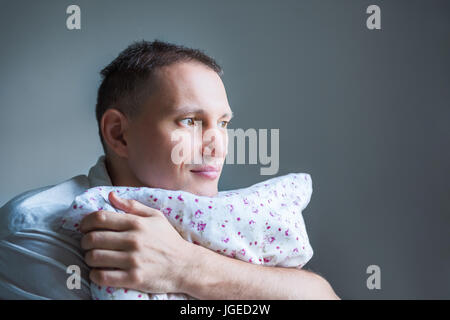 Großansicht Seite Profilbildnis von junger Mann hält ein Kissen suchen und denken Stockfoto