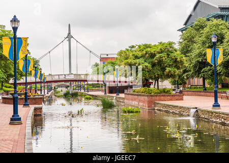 Friedrich, USA - 24. Mai 2017: Carroll Creek in Maryland Stadtpark mit Kanal, Reflexion und Passanten, die durch eine Brücke mit Schild Stockfoto