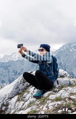 Weibliche Wanderer machen ein Selbstporträt mit ihrem Smartphone mit Hügeln im Hintergrund Stockfoto
