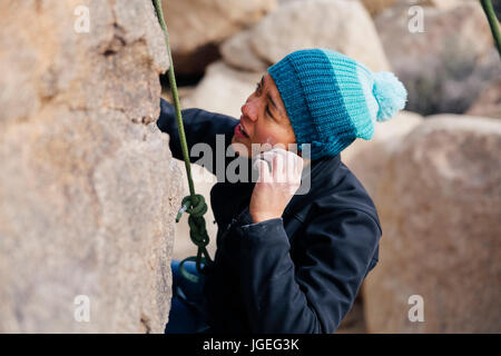 Junge Mischlinge Frau gekleidet für kaltes Wetter Felsen klettert in der Wüste Stockfoto