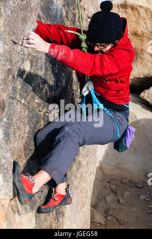 Kaukasische Mädchen mit Brille für kaltes Wetter Rock gekleidet klettert in der Wüste Stockfoto