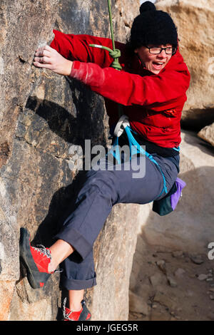 Kaukasische Mädchen mit Brille für kaltes Wetter Rock gekleidet klettert in der Wüste Stockfoto