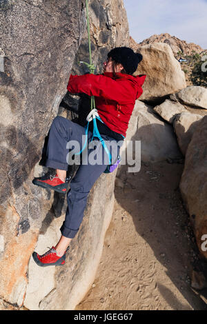 Kaukasische Mädchen mit Brille für kaltes Wetter Rock gekleidet klettert in der Wüste Stockfoto