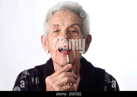 Alte Frau ihre Lippen auf weißem Hintergrund malen Stockfoto