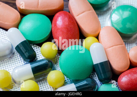 Auf dem Tisch liegen verschiedene Arten von Tabletten zur Behandlung. Tabletten in verschiedenen Formen und Farben. Stockfoto