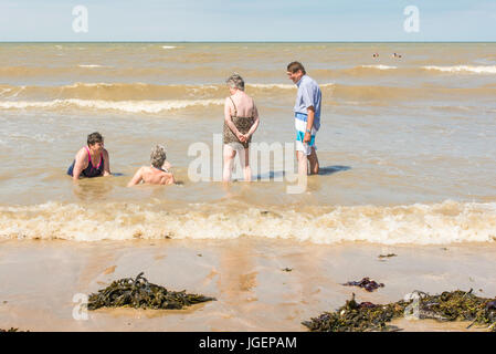 Vier ältere Menschen im Meer, am Wasser, am Strand von Westbrook Bucht, Margate, Kent an einem sonnigen Tag. Stockfoto