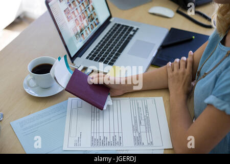 Nahaufnahme des weiblichen executive Holding Tickets und Reisepass an ihrem Schreibtisch im Büro Stockfoto