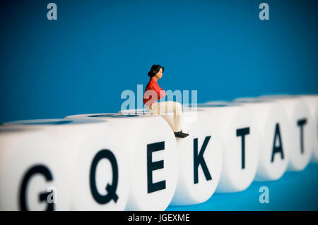 Frau Figur sitzt auf Alphabet Buchstaben, Kommunikation und Sprache-Konzept Stockfoto