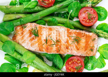 Eine Nahaufnahme von einen Teller mit gegrillter Lachs mit grünem Spargel, Kirschtomaten und Feldsalat, eine gesunde Ernährung-Gericht Stockfoto