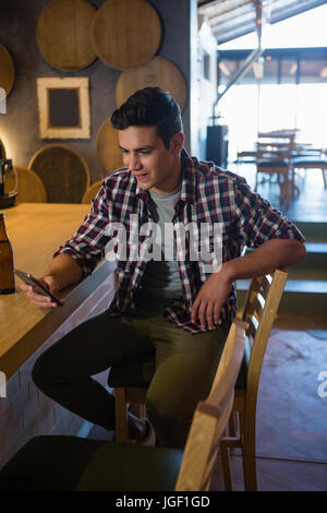 Junger Mann mit Handy sitzend auf Stuhl im restaurant Stockfoto