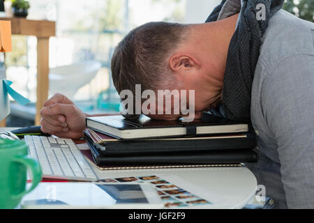 Frustrierte Menschen schlafen auf Dateien am Schreibtisch im Büro Stockfoto