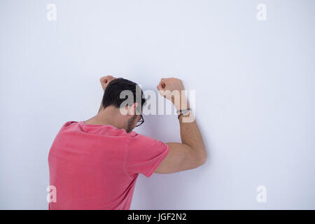 Deprimiert männliche Führungskraft mit erhobenen Armen stützte sich auf der Wand im Büro Stockfoto