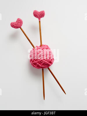 Lieben Sie stricken. Rosa stricken Wolle und Stricknadeln. Stricknadeln mit Häkeln rosa Herzen. Stockfoto