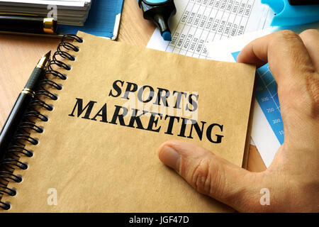 Hände halten Buch mit Titel Sportmarketing. Stockfoto