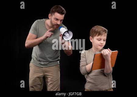 Vater mit Megaphon schreien an kleinen Sohn mit digital-Tablette, Familienprobleme Konzept Stockfoto