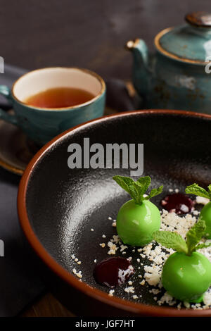 Leckeres Restaurant Dessert aus Äpfeln, Schokolade, Minze und Karamel glasiert in Form von kleinen Äpfel mit Blättern. Dessert vom Chef. Serviert mit Teekanne Stockfoto