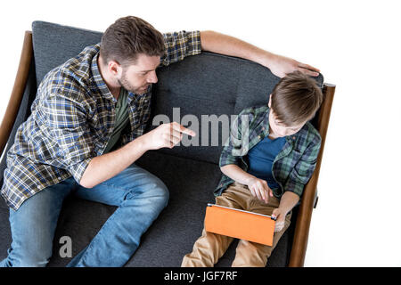 Erhöhte Ansicht der Vater sitzt auf dem Sofa und zeigt mit Finger auf Sohn mit digital-Tablette, Familienprobleme Konzept Stockfoto