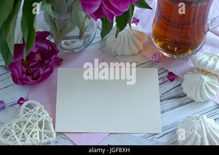 Päonien Blüten rosa Glas Tee mit Grußkarte Marshmallow auf weißem Hintergrund Holz-stock Bild Stockfoto