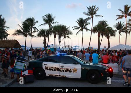 Broward County Sheriff Polizeiauto Lichter blinken in Deerfield Beach, Florida nach Sonnenuntergang vor Barrikaden und Menschenmenge, 4. Juli 2017 Stockfoto