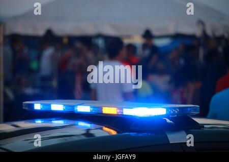 Gelbe und blaue Lichter auf Polizeiauto beleuchtet während blinkt nach Einbruch der Dunkelheit in Deerfield Beach, Florida mit Menschen und Hersteller Zelte am 4. Juli 2017 Stockfoto